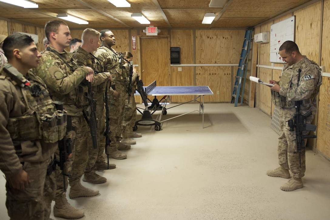 Air Force Tech. Sgt. Axel Rodriguez, right, performs roll call and mission brief during guard mount on Kandahar Airfield, Afghanistan, Jan. 21, 2016. Rodriguez is a security day-shift flight chief assigned to the 451st Expeditionary Support Squadron Security Forces Flight. Guard mount is conducted at the start of a shift and may be used to conduct roll call, announcements, weapons and equipment inspections or post assignments. U.S. Air Force photo by Tech. Sgt. Robert Cloys