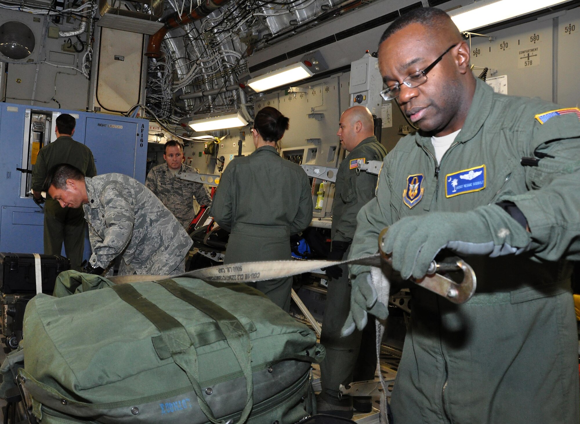 Ministry of presence - Chaplain (Lt Col.) Ronald Apollo (left), 315th Airlift Wing, assists Chief Master Sgt. Reggie Godbolt, 300th Airlift Squadron loadmaster superintendent, as he ties down bags on a recent training mission to Ramstein AB, Germany. (U.S. Air Force Photo by Maj. Wayne Capps)