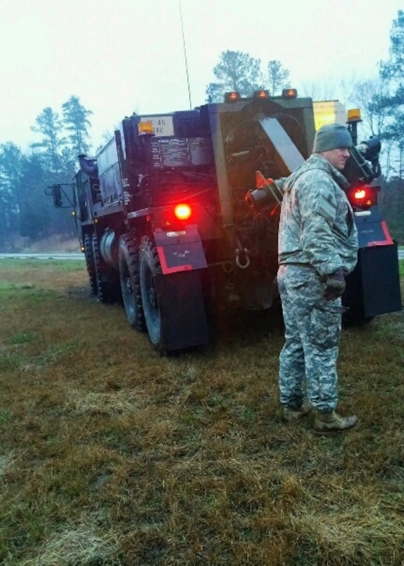 A soldier assists as a wrecker vehicle pulls a disabled truck out of a ditch during winter snow storm response operations in Spartanburg, South Carolina, Jan 23, 2016. South Carolina National Guard photo