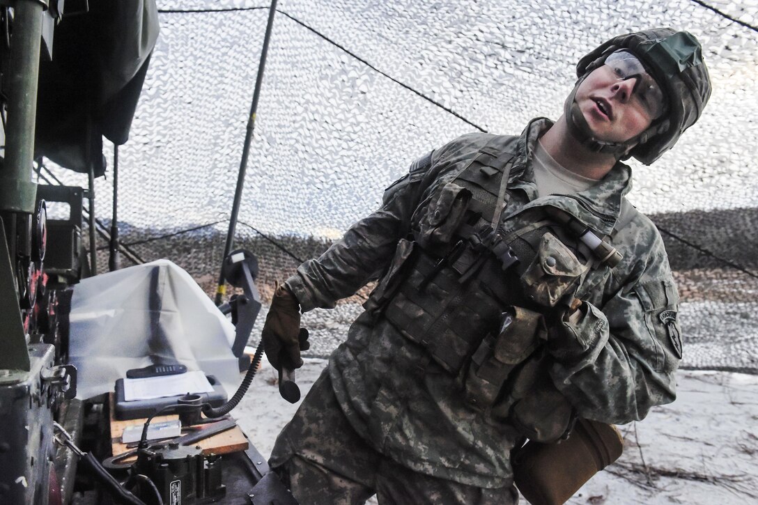 Army Sgt. Lukas Couvaras relays a radio transmission while conducting M119A2 105mm howitzer live-fire training on Joint Base Elmendorf-Richardson, Alaska, Jan. 11, 2016.. Couvaras is assigned to the 25th Infantry Division’s 2nd Battalion, 377th Parachute Field Artillery Regiment, 4th Infantry Brigade Combat Team, Airborne, Alaska. U.S. Air Force photo by Alejandro Pena