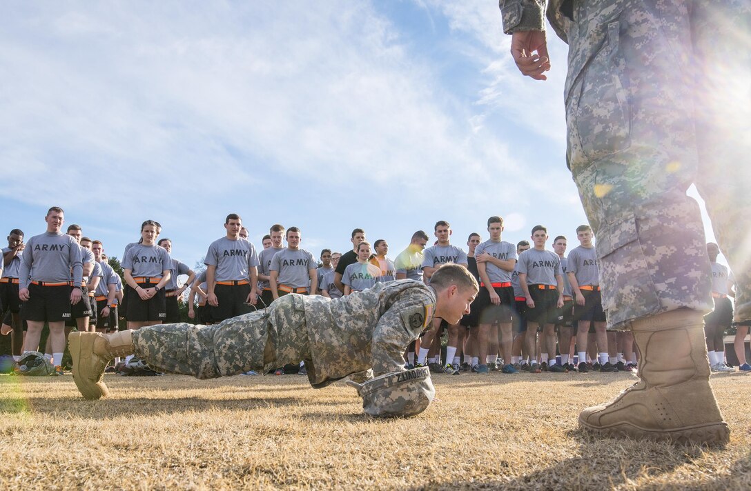 Army ROTC cadet Michael Chaitovitz, center, demonstrates the proper way to do pushups for freshman and sophomore cadets before they participate in an Army Physical Fitness Test at Clemson University, S.C., Jan. 14, 2016. U.S. Army photo by Staff Sgt. Ken Scar  