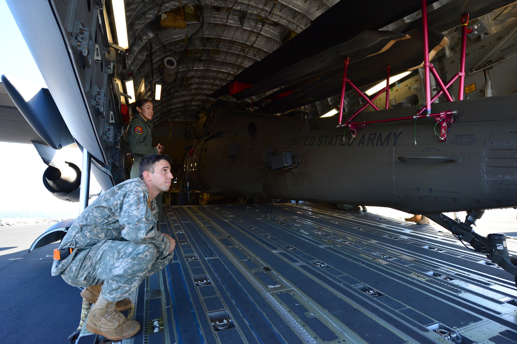 Army Spc. Mohamed Bouteldja, from the 25th Combat Aviation Brigade Schofield Barracks, and Air Force Staff Sgt. Alicin Muro, a loadmaster from the 535th Airlift Squadron, assist with the loading of a UH-60 Black Hawk, from the 25th CAB, into a C-17 Globemaster III, from the 535th AS, on Joint Base Pearl Harbor-Hickam, Hawaii, Jan. 21, 2016. Three UH-60 were loaded on to the C-17 as part of recurring training between the Air Force and Army. (U.S. Air Force photo by Tech. Sgt. Aaron Oelrich/Released)