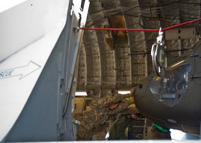 Soldiers, from 25th  Combat Aviation Brigade Schofield Barracks, and Airmen, from 535th Airlift Squadron, push a  UH-60 Black Hawk into position inside a C-17 Globemaster III, from the 535th AS, on Joint Base Pearl Harbor-Hickam, Hawaii, Jan. 21, 2016. Three UH-60 were loaded on to the C-17 as part of recurring training between the Air Force and Army. (U.S. Air Force photo by Tech. Sgt. Aaron Oelrich/Released)
