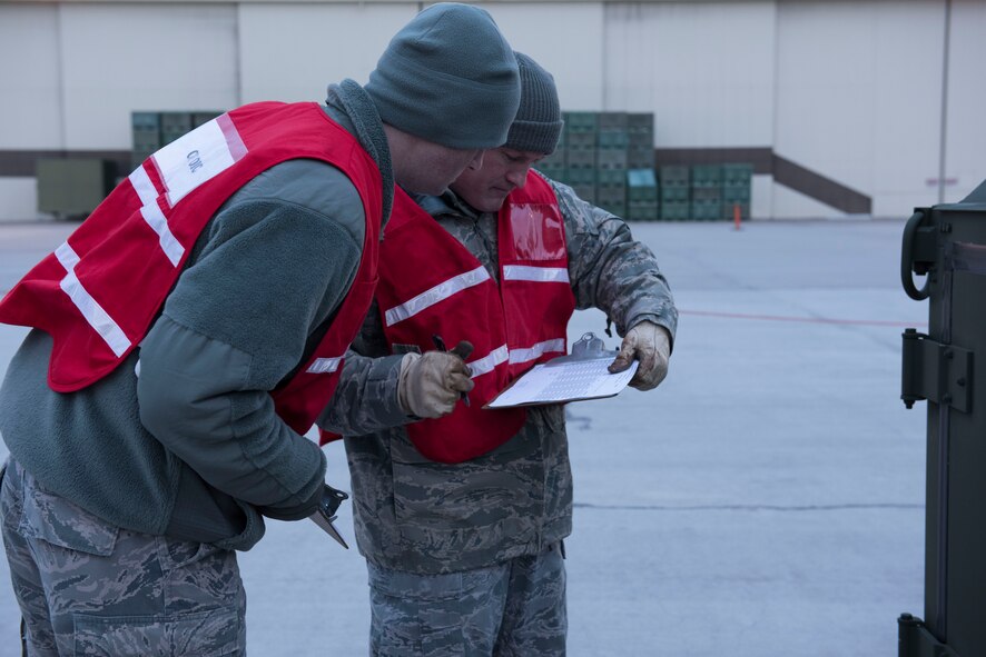 Tech. Sgt. Travis Hughes (right), 366th Logistics Readiness Squadron float yard augmentee, and 2nd Lt. Chase Barnes (left), 366th Logistics Readiness Squadron officer in-charge, check a cargo list, Jan. 22, 2016, at Mountain Home Air Force Base, Idaho. Barnes and Hughes coordinated and supervised all aircraft, personnel and vehicle loading operations. (U.S. Air Force photo by Senior Airman Lauren-Taylor Levin/RELEASED)