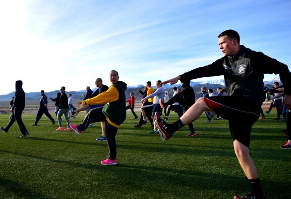 Airmen stretch their hamstrings during the Warrior Trained Fitness event Jan. 25, 2016, at Creech Air Force Base, Nevada. The event was part of the Life of a Warrior and challenged Airmen to complete a series of circuits which included many different callisthenic and cardiovascular exercises. (U.S. Air Force photo by Senior Airman Christian Clausen/Released)