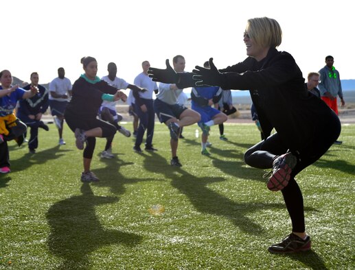 Heidi, a trainer for Nellis AFB, Nevada, demonstrates a stretch to Airmen after the Warrior Trained Fitness event Jan. 25, 2016, at Creech Air Force Base, Nevada. The event was part of the Life of a Warrior campaign which aims to help Airmen in every pillar of resiliency, spiritual, social, mental, and physical, by providing opportunities to come together, interact, work out, and even compete in competition. (U.S. Air Force photo by Senior Airman Christian Clausen/Released)