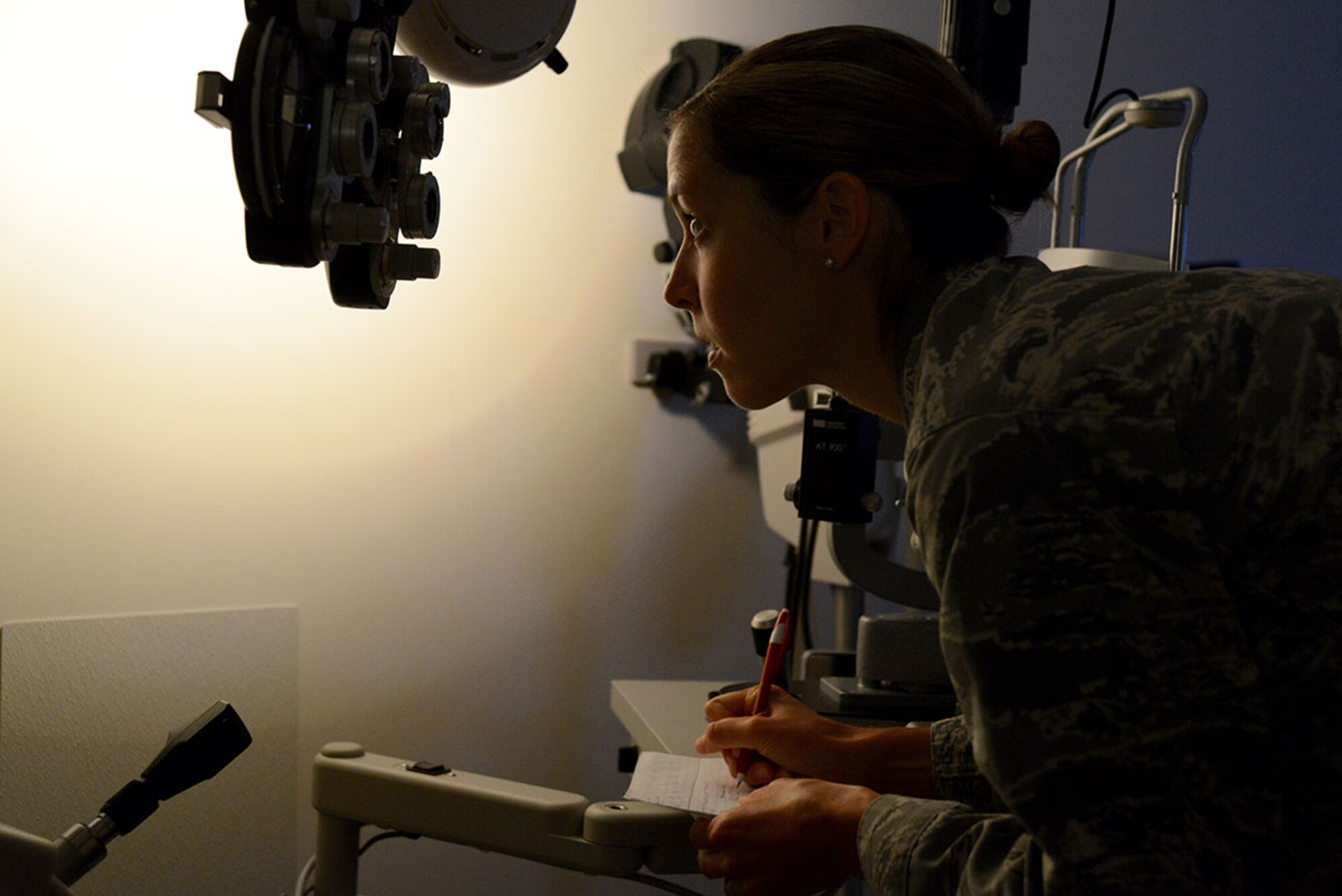 Air Force Capt. Lauren Fundler, 673d Medical Group optometrist, checks the phoropter and writes down a prescription at Joint Base Elmendorf-Richardson hospital, Aug. 11, 2015. Optometry is one of the 18 career fields which make up the Biomedical Sciences Corps. (U.S. Air Force photo by Airman Christopher R. Morales)