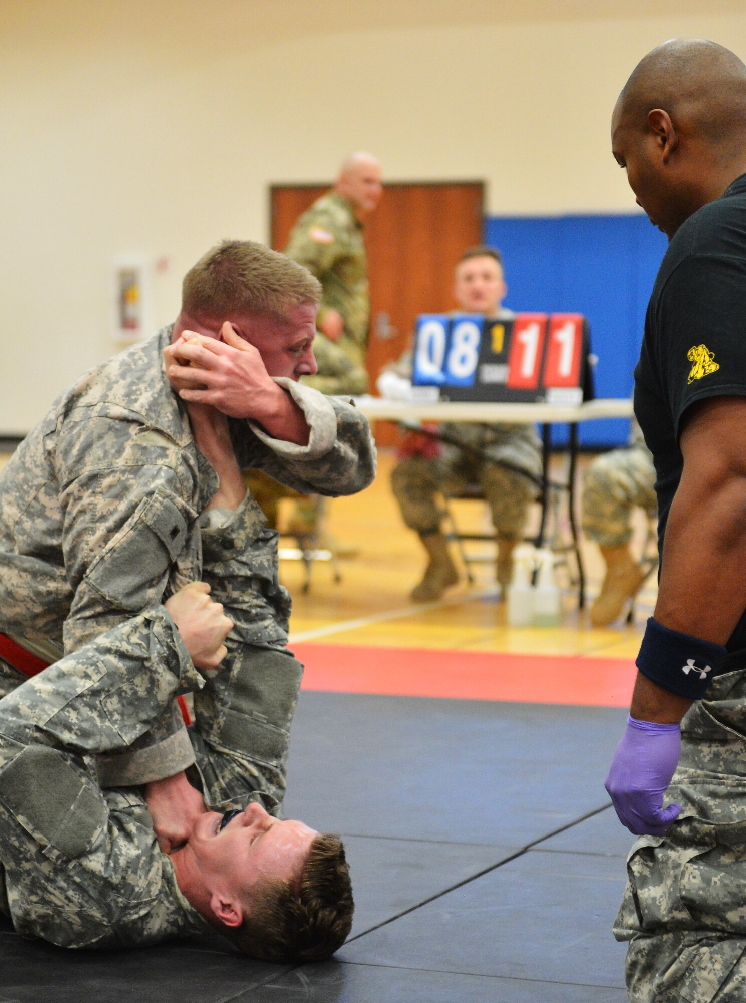 Two U.S. Army 743rd Military Intelligence Battalion Squadron soldiers battle for control while a referee looks on during a combatives tournament at the Buckley Fitness Center Jan. 22, 2015, on Buckley Air Force Base, Colo. The army battalion hosts the tournament every year to hone hand-to-hand combat training techniques while engaging in friendly competition. (U.S. Air Force photo by Staff Sgt. Darren Scott/Released)
