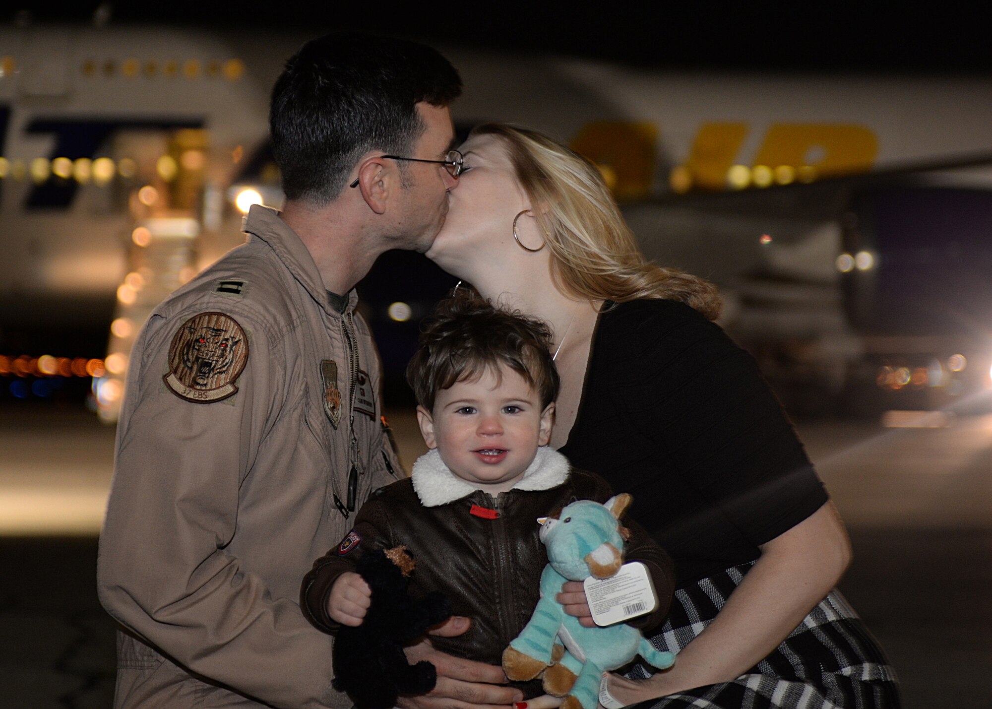 Capt. Cameron, 28th Aircraft Maintenance Squadron pilot, kisses his wife, Jessie, in front of aircraft Atlas after returning from a deployment to Southwest Asia at Ellsworth Air Force Base, S.D., Jan. 24, 2016. During the rotation, Ellsworth Airmen provided operational support to the 379th Air Expeditionary Wing by providing theater commanders with critical long-range strike capability and persistent presence. (U.S. Air Force photo by Airman Sadie Colbert/Released)