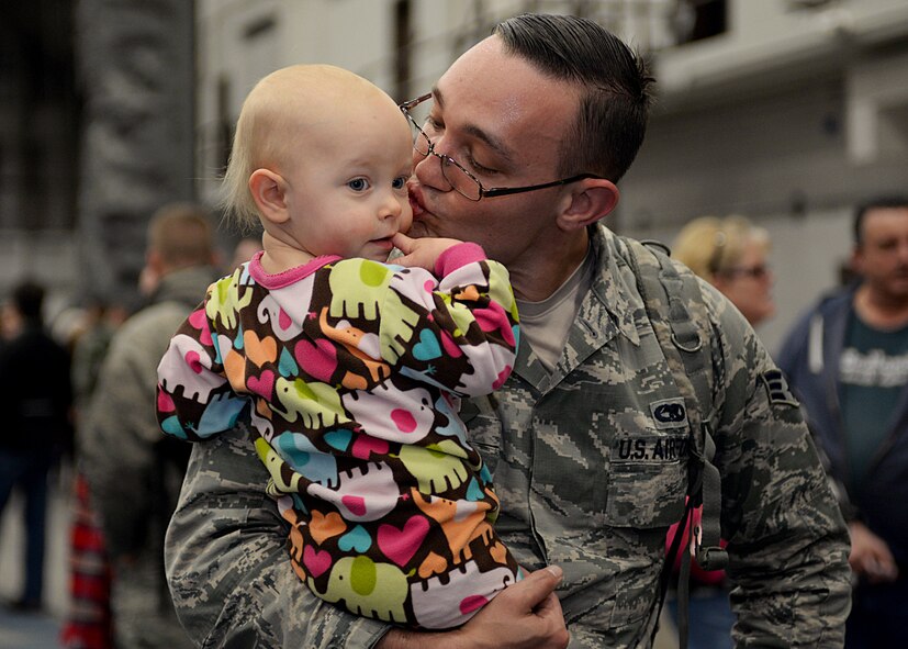 Senior Airman Joseph, 28th Maintenance Group weapons systems controller, kisses his daughter, Aerin, during a homecoming celebration at Ellsworth Air Force Base, S.D., Jan. 24, 2016. Hundreds of family members, loved ones and fellow Airmen gathered on the flightline to greet Airmen home after more than six months of B-1 bomber combat operations in the U.S. Central Command area of responsibility. (U.S. Air Force photo by Airman Sadie Colbert/Released)