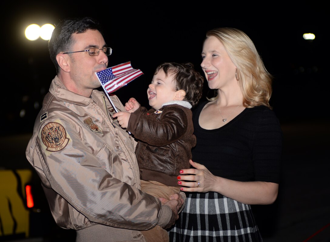 Capt. Cameron, 37th Bomb Squadron pilot, embraces his spouse, Jessie, and son, Julian, at Ellsworth Air Force Base, S.D., Jan. 24, 2016. Ellsworth Airmen provided operational support to the 379th Air Expeditionary Wing during their deployment and flew a total of 490 sorties during this rotation, employing more than 4,850 munitions in the past six months. (U.S. Air Force photo by Airman Donald C. Knechtel/Released)