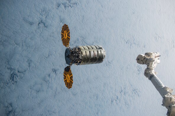 Using the International Space Station's robotic arm, Canadarm2 (right) NASA Flight Engineer Kjell Lindgren prepares to capture Orbital ATK's Cygnus cargo vehicle Dec. 09, 2015. The space station crew and the robotics officer in mission control in Houston positioned Cygnus for installation to the orbiting laboratory's Earth-facing port of the Unity module. The connection to the port uses a common berthing mechanism that was developed by testing at AEDC. Among the more than 7,000 pounds of supplies aboard Cygnus are numerous science and research investigations and technology demonstrations, including a new life science facility that will support studies on cell cultures, bacteria and other microorganisms; a microsatellite deployer and the first microsatellite that will be deployed from the space station; several other educational and technology demonstration CubeSats; and experiments that will study the behavior of gases and liquids, clarify the thermo-physical properties of molten steel, and evaluate flame-resistant textiles. (NASA photo)