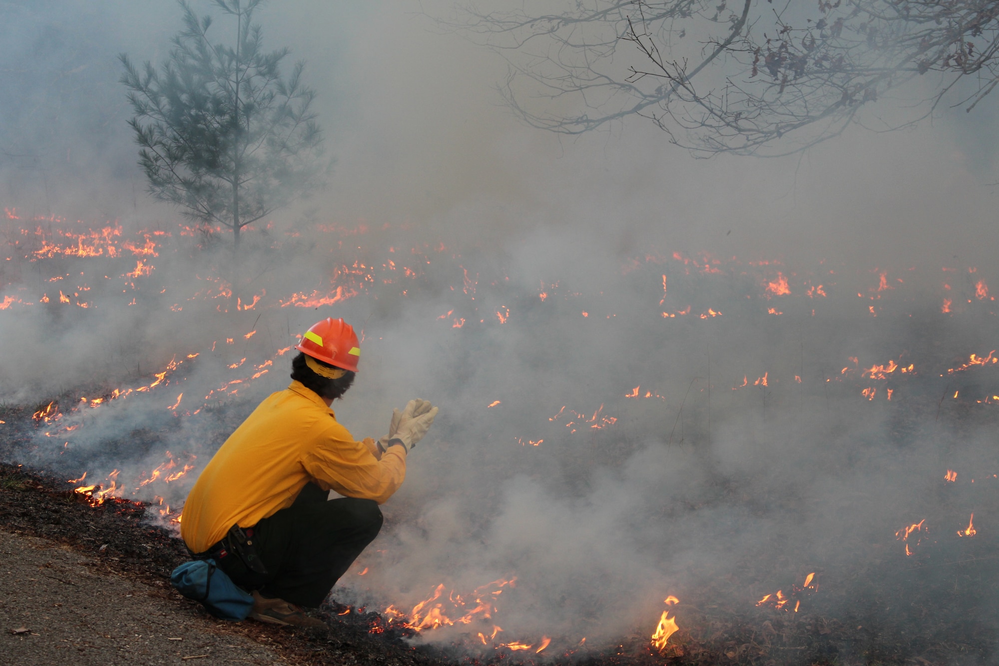 A course participant in the wildland fire training takes a chance to warm up while watching how the flames react to the windy conditions. (U.S. Air Force photo/Deidre Ortiz)