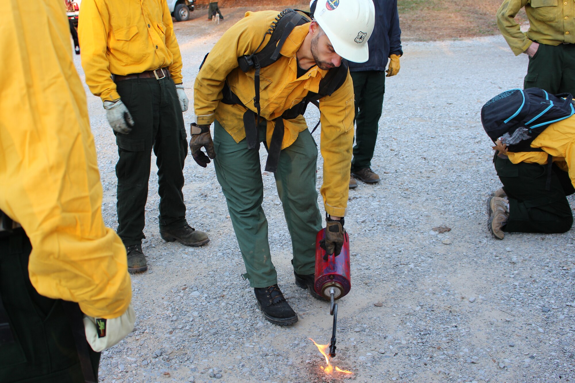 Wildland fire instructor Brent Foltz with the U.S. Forest Service shows the basic wildland training course participants how to assemble and light the torch used during a live fire exercise that took place as part of the basic wildland fire training course held at University of the South. (U.S. Air Force photo/Deidre Ortiz)