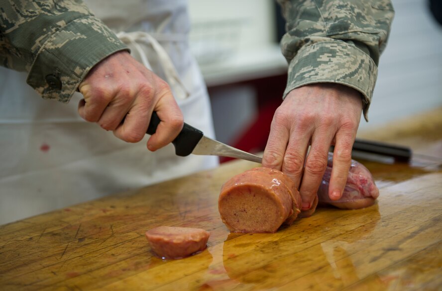 Chief Master Sgt. Geoff Weimer, 5th Bomb Wing command chief, cuts meat at the Sportsmen Feed cut-up event at Bloms’ Locker & Processing in Minot, N.D., Jan. 22, 2015. The cut-up event preceeds the Sportsmen Feed event on base, which features an array of wild game. (U.S. Air Force photo/Senior Airman Apryl Hall)