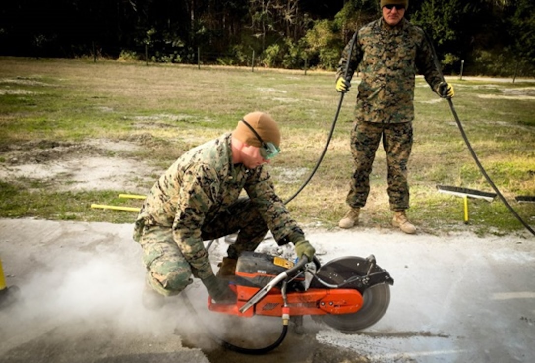 On January 19, 2016 Second Lieutenant Matt Bergman, a student with Combat Engineer Officer's course 3-16 (CEO 3-16); uses a cut-off saw to aid in the repairing of a spall at the airfield damage repairs site located at Court House Bay, Camp Lejeune, N.C. A spall is known as pavement damage that is no more then 5 feet in diameter and does not penetrate into sub-grade material. Gunnery Sergeant Jessie McDonald, a Combat Engineer Instruction Company instructor; holds the saws cord while supervising the training.
