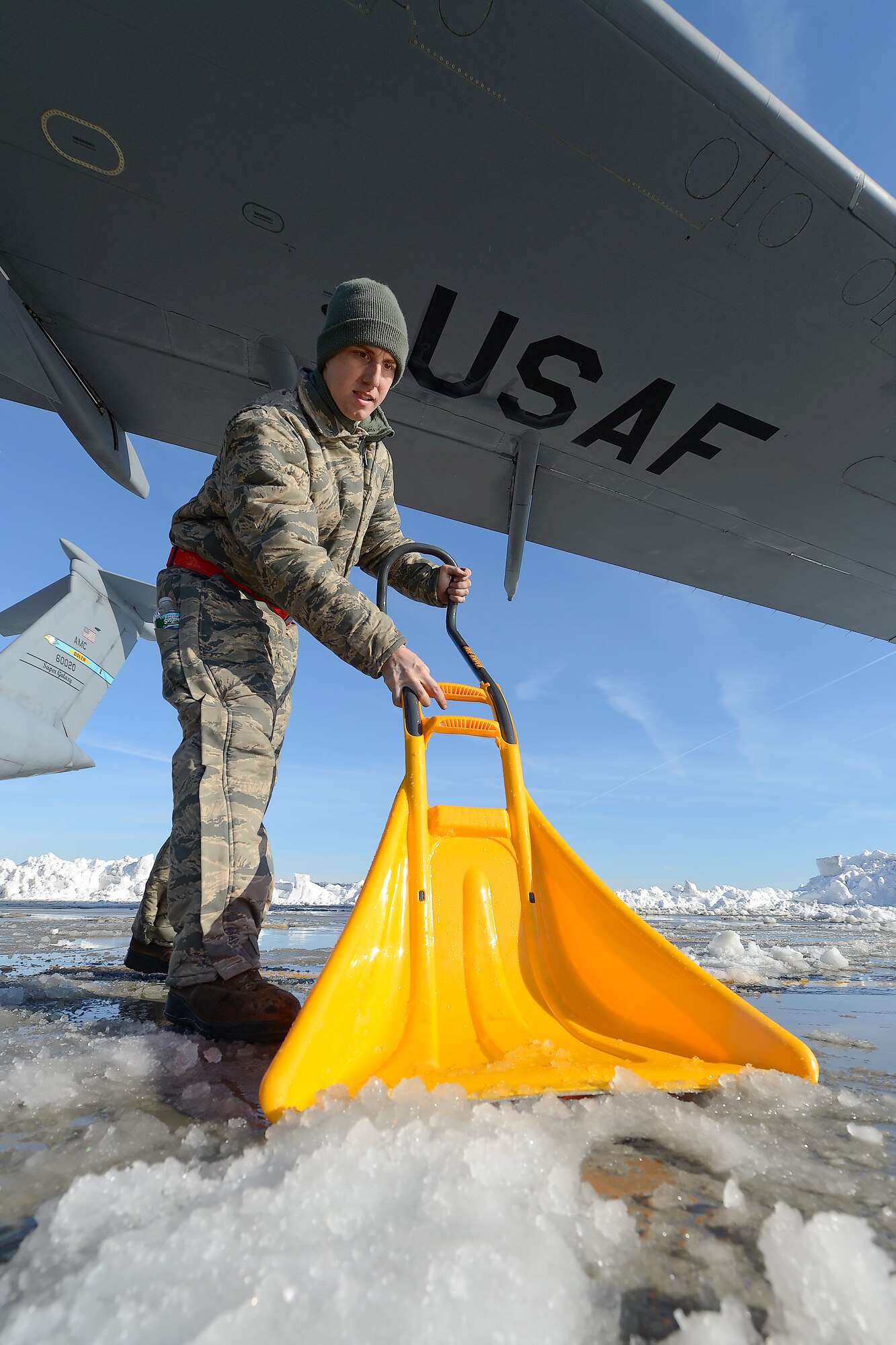Senior Airman Joshua Forren, 436th Aircraft Maintenance Squadron, C-5M Super Galaxy crew chief, shovels ice under the wing of a C-5M Super Galaxy of the 436th Airlift Wing, after Winter Storm Jonas Jan. 25, 2016, at Dover Air Force Base, Del. Heavy equipment along with hand shovels were used to clear 22 inches of accumulated snow from the flight line as the base worked to quickly resume flight operations. (U.S. Air Force photo/Greg L. Davis)