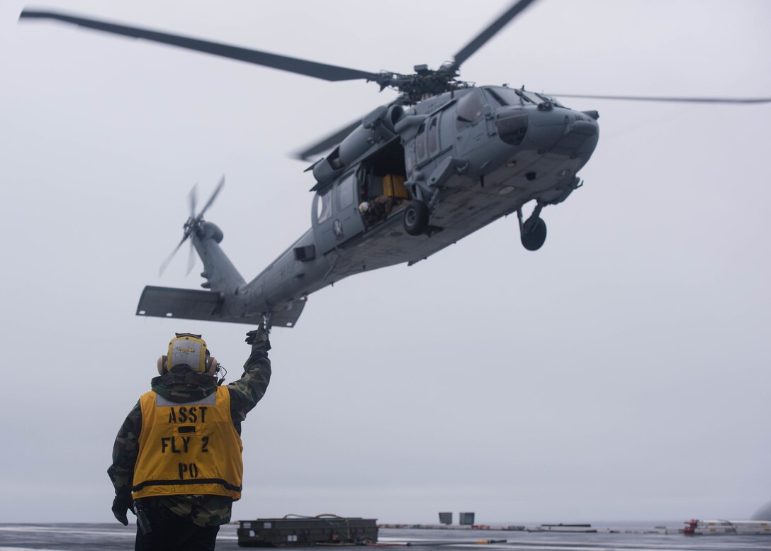Navy Petty Officer 2nd Class Randy Morta directs a Navy MH-60S Sea Hawk helicopter assigned to the Helicopter Sea Combat Squadron 14 as it lands on the flight deck of USS John C. Stennis during a replenishment at sea with USNS Rainier in the Pacific Ocean, Jan. 18, 2016. Morta is an aviation boatswain's mate handling. U.S. Navy photo by Petty Officer 3rd Class Kenneth Rodriguez Santiago