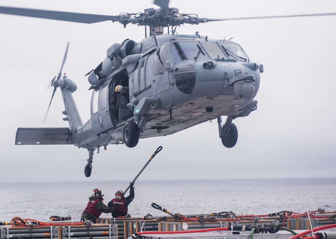 On the flight deck of USS John C. Stennis, Navy Petty Officer 1st Class Charles Robinson and Seaman Vernon Henderson prepare to hook a Navy MH-60S Sea Hawk helicopter assigned to Helicopter Sea Combat Squadron 14 during a replenishment at sea in the Pacific Ocean, Jan. 18, 2016. The helicopter was transporting ordnance to USNS Rainier. Robinson is an aviation ordnanceman and Henderson is an aviation ordnanceman airman. U.S. Navy photo by Petty Officer 3rd Class Kenneth Rodriguez Santiago
