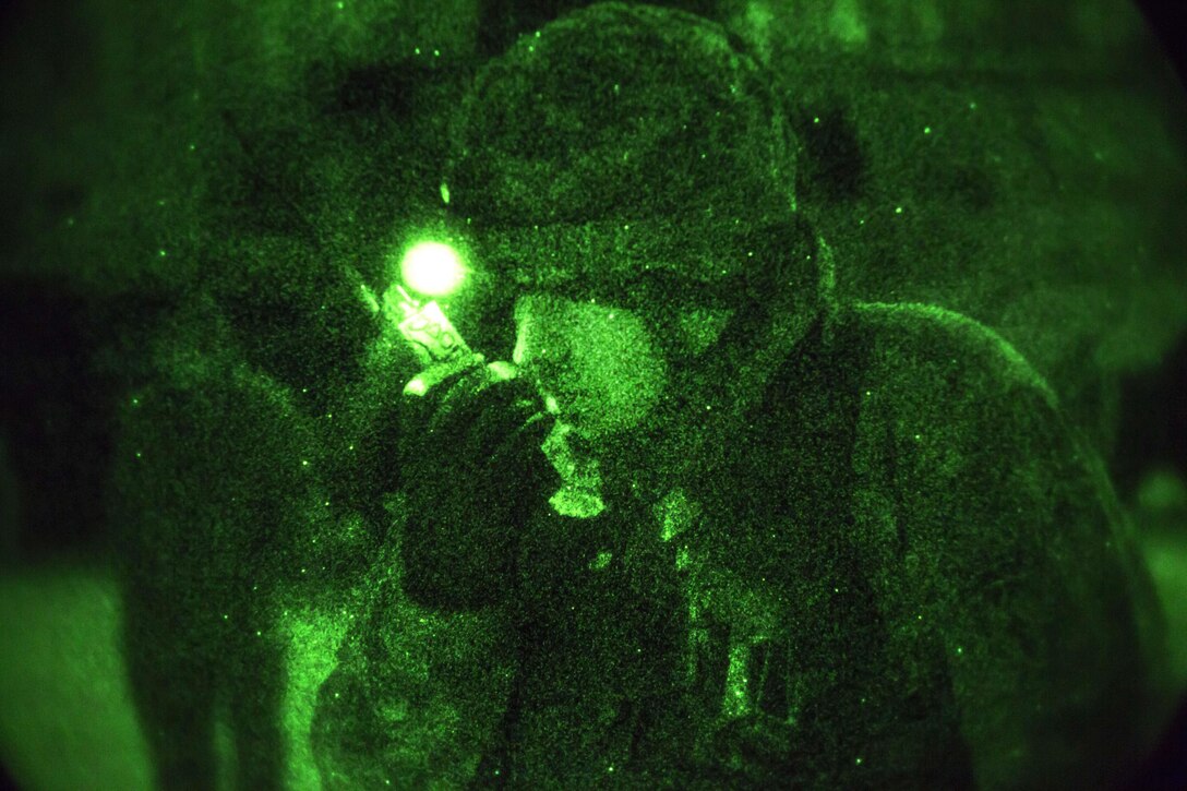 As seen through a night-vision device, a paratrooper relays information while conducting night jump operations at Malemute drop zone on Joint Base Elmendorf-Richardson, Alaska, Jan. 21, 2016. U.S. Air Force photo by Alejandro Pena