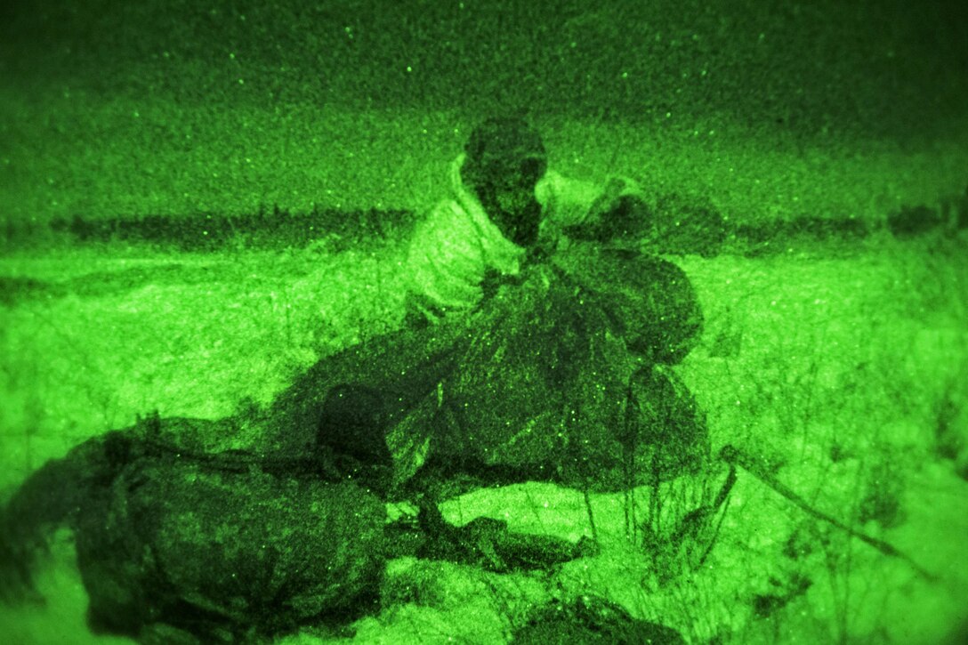 As seen through a night-vision device, a paratrooper recovers his parachute after completing a night jump onto Malemute drop zone on Joint Base Elmendorf-Richardson, Alaska, Jan. 21, 2016. U.S. Air Force photo by Alejandro Pena
