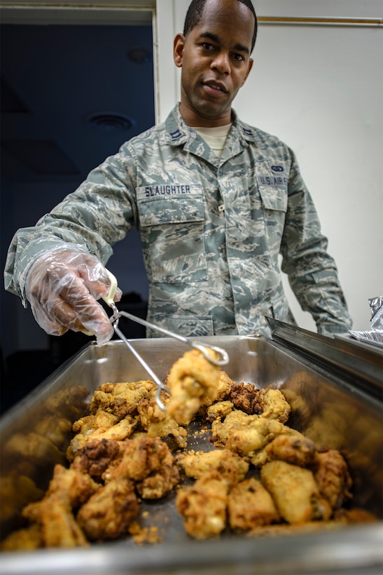 Capt. Kevin Slaughter, a 71st Student Squadron section leader, serves up some chicken wings during a SIGMO at Vance Air Force Base, Oklahoma, Jan. 25. Traditionally, leaders from across the base don the gloves and serve single and unaccompanied Airmen at the community meals. The Vance Chaplain's office has hosted SIGMOs for almost 20 years. (U.S. Air Force photo / David Poe)