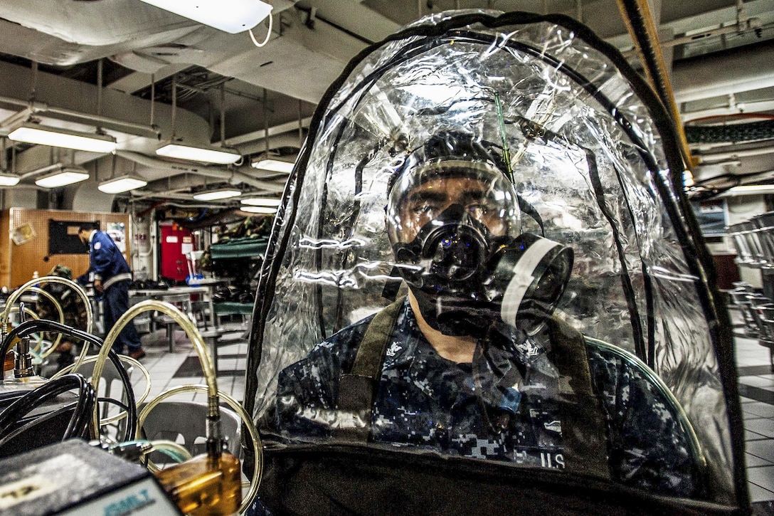 U.S. Navy Petty Officer 2nd Class Adalbert Guiterrez sits in a gas chamber with equipment to detect if his mask has a proper seal aboard the aircraft carrier USS Ronald Reagan in Yokosuka, Japan, Jan. 26, 2016. His mask is designed to withstand chemical, biological and radiological threats. The Reagan provides a combat-ready force to protect and defend the maritime interests of the United States and its allies and partners in the Indo-Asia-Pacific region. U.S. Navy photo by Petty Officer 3rd Class Nathan Burke 

