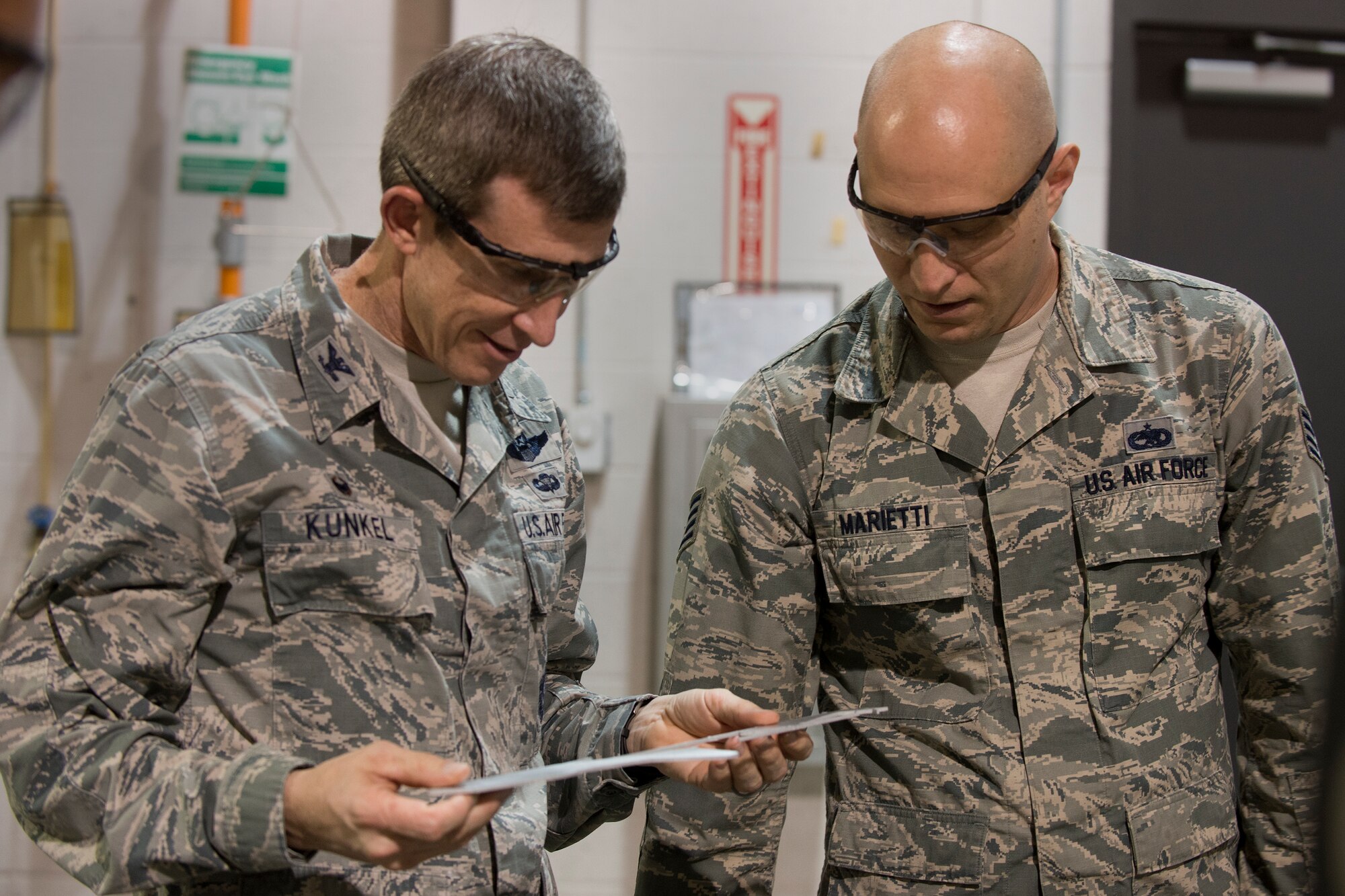 U.S. Air Force Staff Sgt. Ian Marietti, 23d Equipment Maintenance Squadron aircraft metals technology craftsman, right, presents Col. Thomas Kunkel, 23d Wing commander, with a memento cut from a water jet machining center, Jan. 25, 2016, at Moody Air Force Base, Ga. Kunkel visited the 23d EMS aircraft metals technology flight to observe their mission and capabilities. (U.S. Air Force photo by Airman Daniel Snider/Released) 
