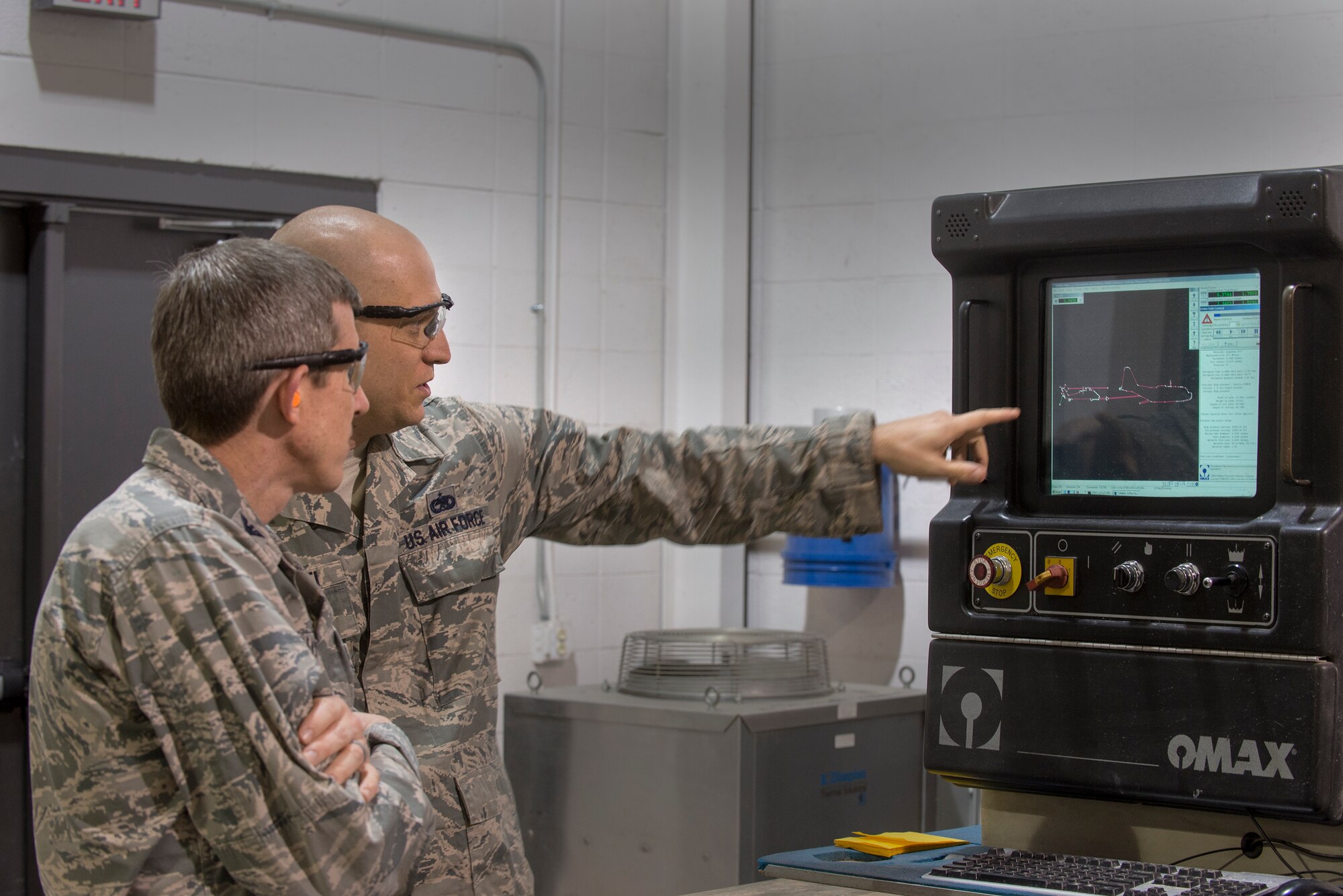 U.S. Air Force Staff Sgt. Ian Marietti, 23d Equipment Maintenance Squadron aircraft metals technology craftsman, right, explains the water jet machining center to Col. Thomas Kunkel, 23d Wing commander, Jan. 25, 2016, at Moody Air Force Base, Ga. The machine has the ability to cut through up to six inches of steel at two and half times the speed of sound. (U.S. Air Force photo by Airman Daniel Snider/Released)
