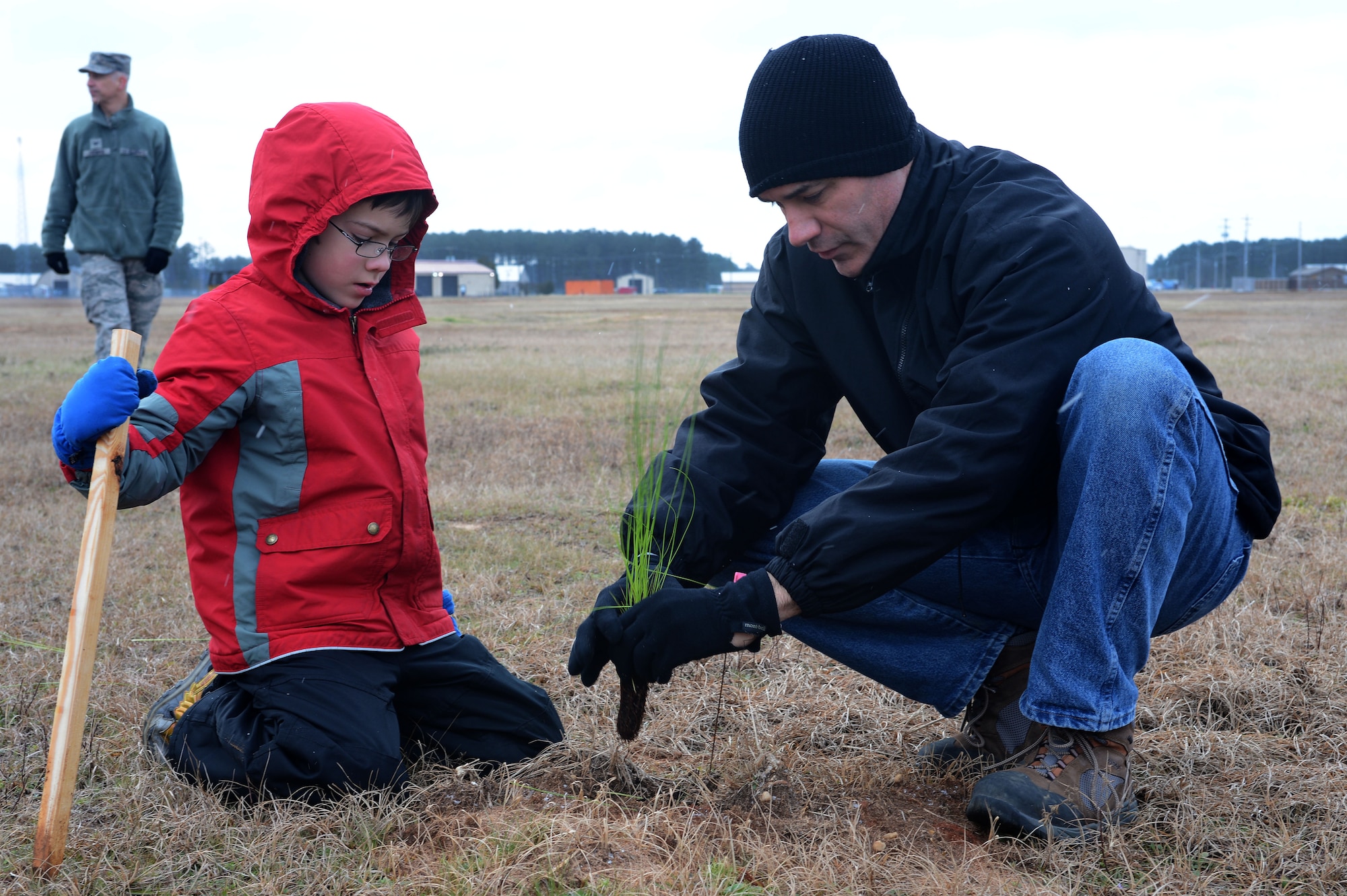 U.S. Air Force Lt. Col. William Miller, U.S. Air Forces Central Command chief of intel integration, and his son Joey, plant longleaf pine saplings at Shaw Air Force Base, S.C., Jan. 23, 2016. More than 20 Team Shaw volunteers and 14 Boy and Cub Scouts helped plant approximately 500 trees around Shaw in an effort to reintroduce the native trees to the local ecosystem after decades of deforestation. (U.S. Air Force photo by Senior Airman Zade Vadnais) 