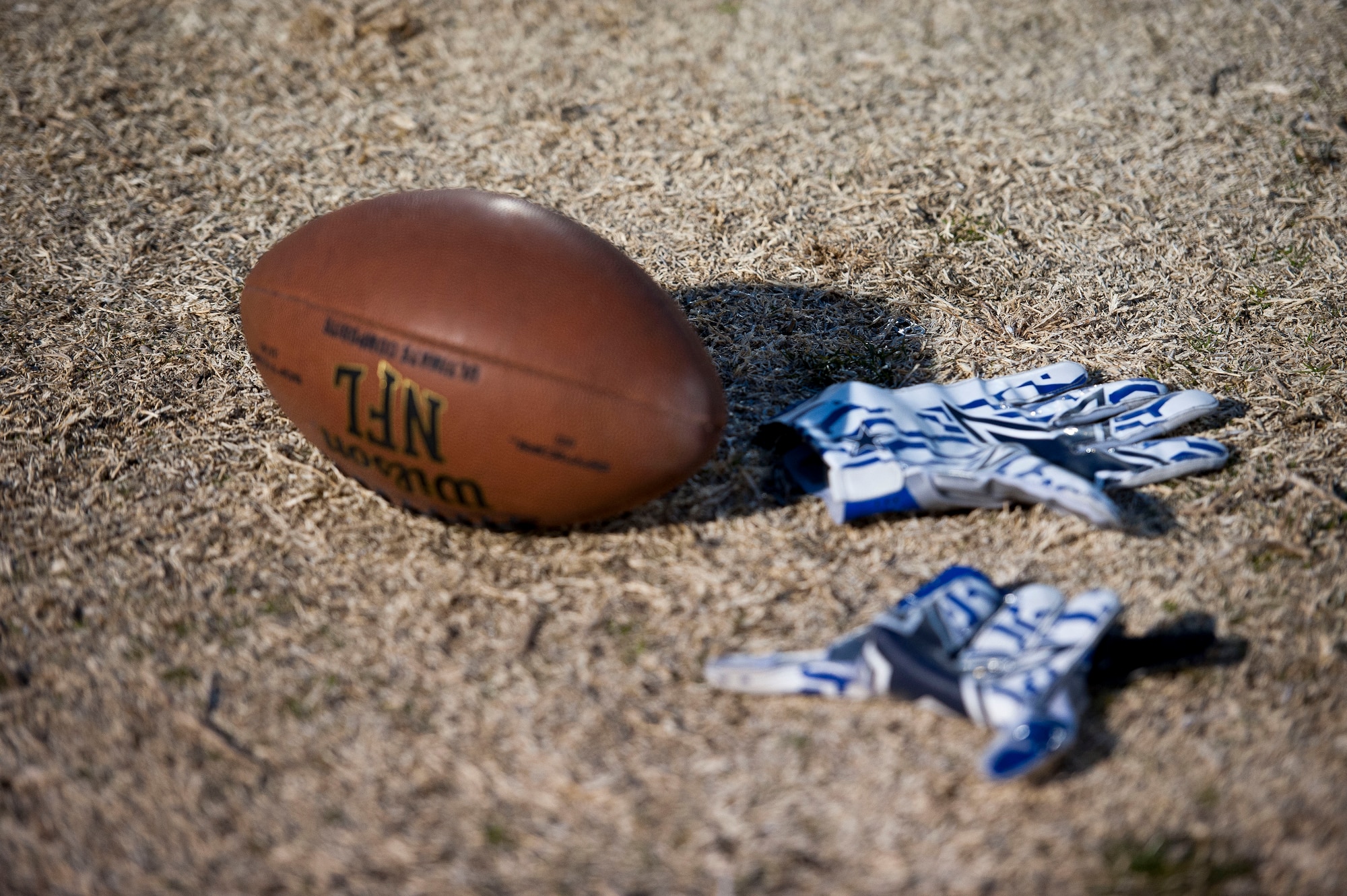 A football and gloves used by the Nellis Air Force Base flag football team lie on the ground at Tropical Breeze Park in North Las Vegas on Jan. 16, 2016. The Nellis Air Force Base flag football team lost in the first round of the tournament on Sunday with a score of 18-19. (U.S. Air Force photo by Senior Airman Mikaley Kline) 