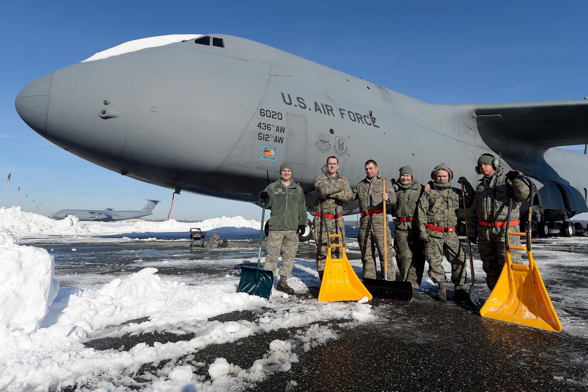 Airmen from the 436th Maintenance Squadron pose with their shovels near the nose of a C-5M Super Galaxy as they take a break from clearing snow and ice from around the aircraft during clearing operations after Winter Storm Jonas Jan. 25, 2016, at Dover Air Force Base, Del. Heavy equipment cleared large open areas while hand-shovels were used near the multi-million dollar aircraft. (U.S. Air Force photo/Greg L. Davis)