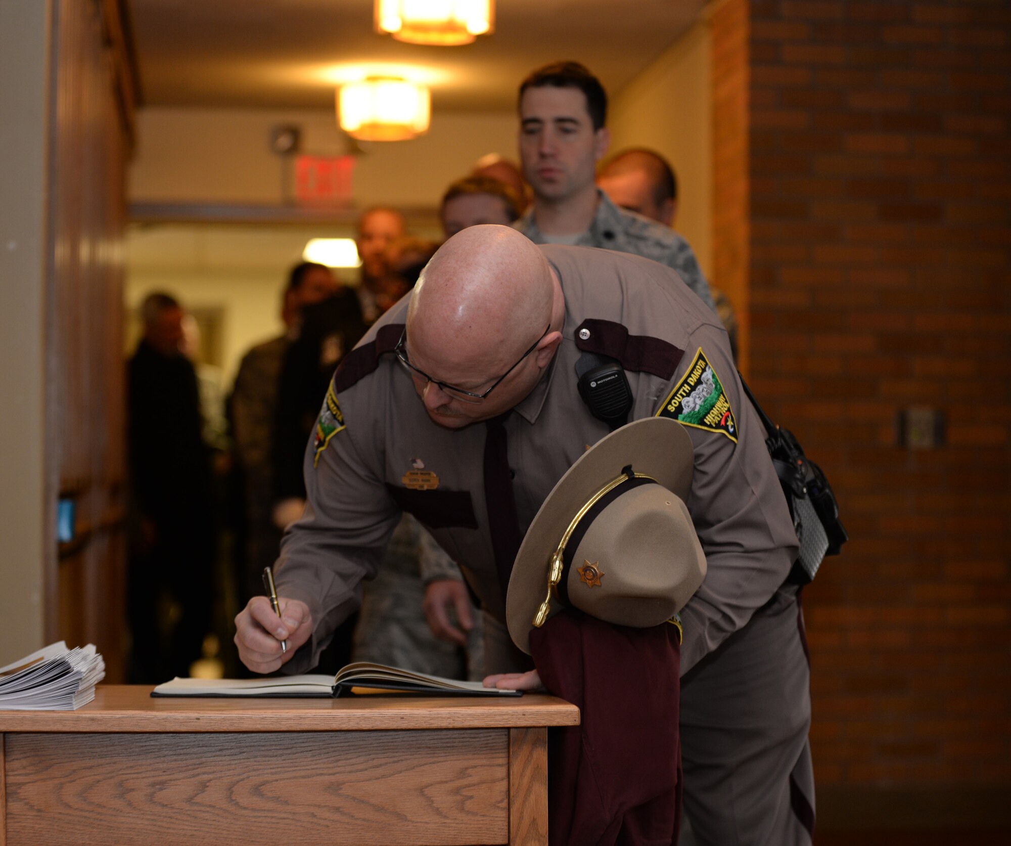 Airmen and members of the Black Hills community sign into the guest book at a memorial service for Special Agent Peter Taub, Air Force Office of Special Investigations Detachment 816 investigator, at Ellsworth Air Force Base, S.D., Jan. 25, 2016. Taub’s contagious smile and personality impacted many lives in the Black Hills community. (U.S. Air Force photo by Airman 1st Class James L. Miller/Released)