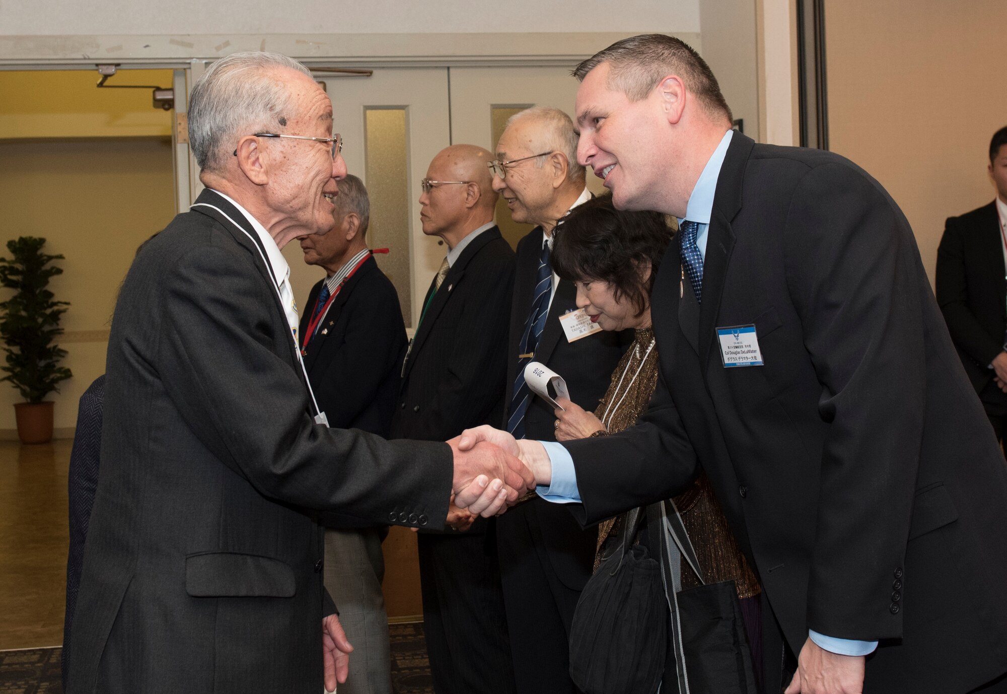 Col. Douglas DeLaMater, 374th Airlift Wing commander, greets with Hiromichi Shimada, member of Hamura-Yokota Friendship Club during the Joint New Year’s Party at Yokota Air Base, Japan, Jan. 23, 2016. The seven Yokota friendship clubs, which include Mizuho town, Fussa city, Akiruno city, Hamura city, Musashimurayama city, Ome city and Akishima city, hosted this event for members of the community to help strengthen U.S. and Japanese relations, and to thank local organizations for their support during the year. (U.S. Air Force photo by Machiko Imai/Released) 