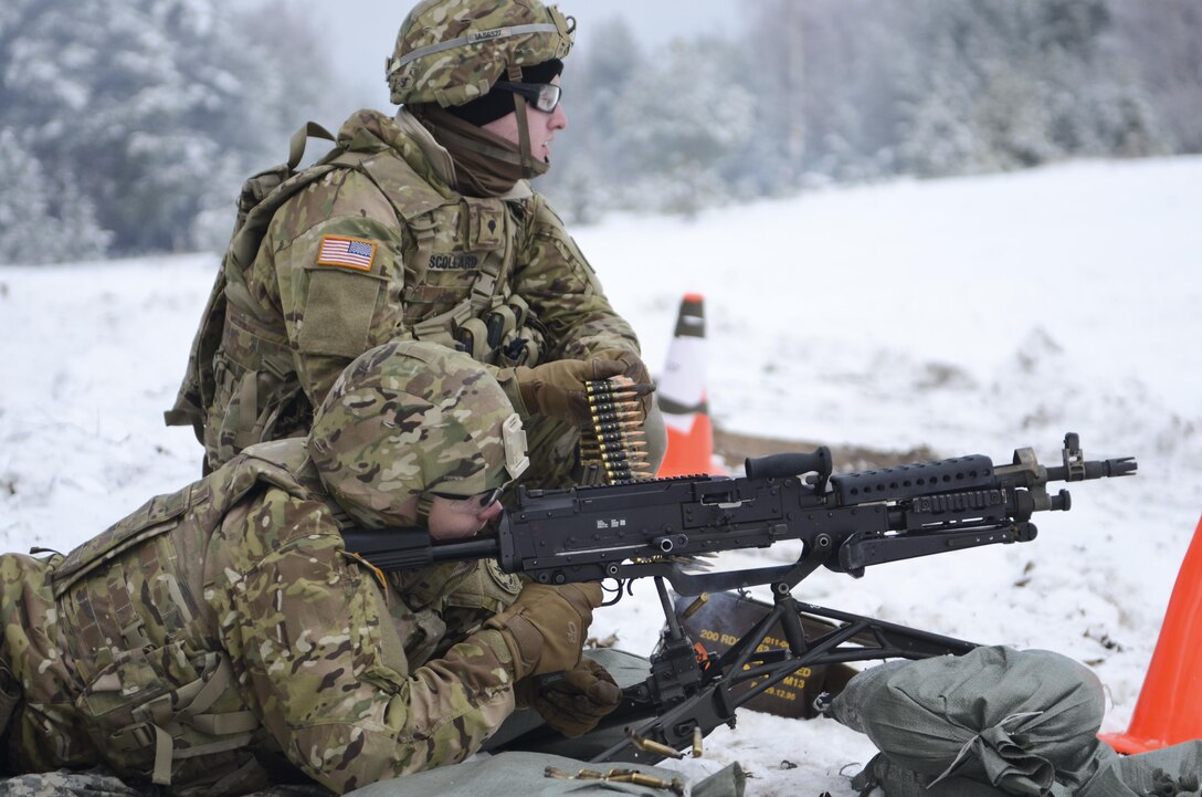 Army Pvt. Gage Adams fires an M240 machine gun as Army Spc. Michael Scollard feeds the ammunition during a training exercise at Adazi Training Area in Latvia, Jan. 25, 2016. Adams, a scout, and Scollard, a radiotelephone operator, are assigned to 3rd Squadron, 2nd Cavalry Regiment. Army photo by Staff Sgt. Steven Colvin