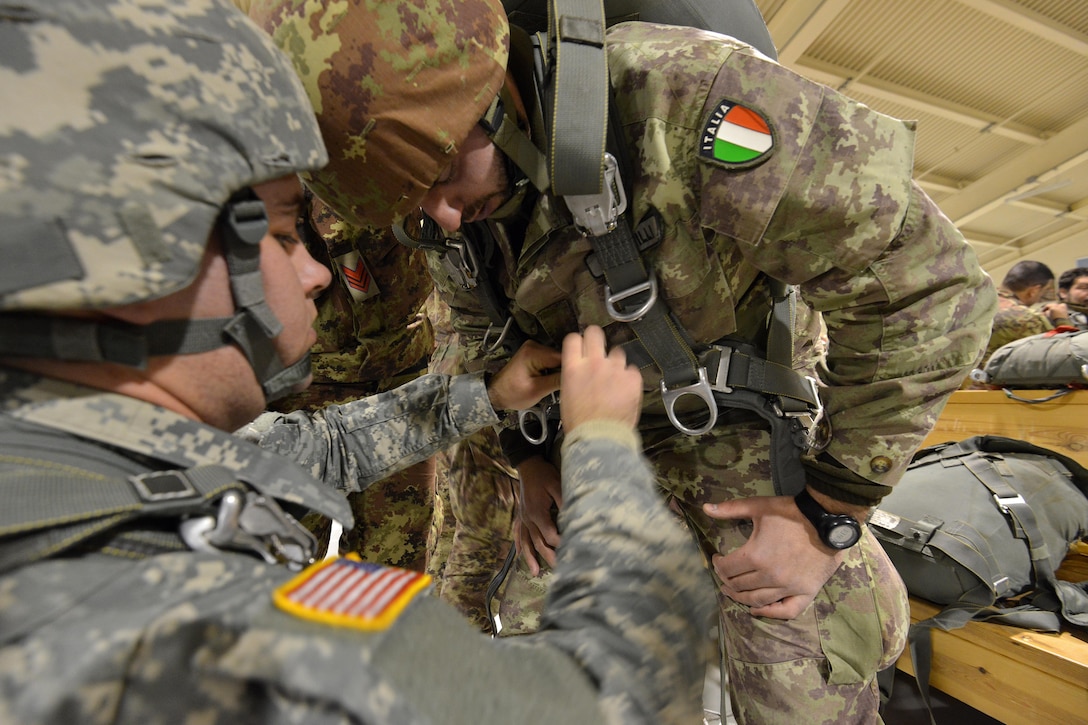 U.S. Army Pvt. John Frommeyer, left, helps Italian army 1st Cpl. Marco Castrilli with his American T-11 parachute before participating in an airborne operation on Aviano Air Base, Italy, Jan. 20, 2016. Frommeyer is a paratrooper assigned to the 54th Brigade Engineer Battalion, 173rd Airborne Brigade, and Castrilli is a paratrooper assigned to the Reparto Comando e Supporti Tattici Paracadutisti. U.S. Army photo by Davide Dalla Massara