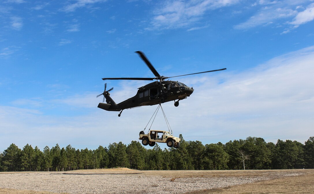 A UH-60 Black Hawk helicopter takes off with a Humvee connected during slingload training on Fort Bragg, N.C., Jan. 20, 2016. Army photo by Sgt. Chad Haling    