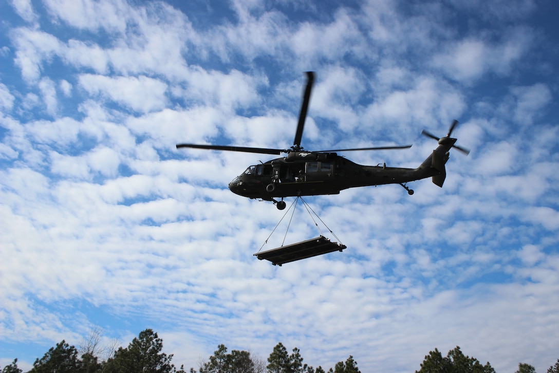 A UH-60 Black Hawk helicopter takes off with a flat rack load connected during slingload training on Fort Bragg, N.C., Jan. 20, 2016. Army photo by Sgt. Chad Haling
