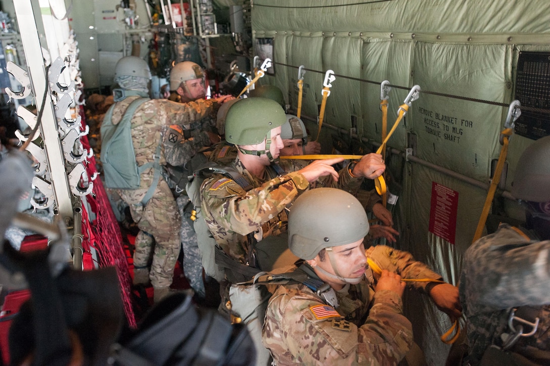 An Army jumpmaster, left, inspects equipment and static lines of paratroopers as they prepare to conduct a static-line parachute jump over a drop zone on Eglin Air Force Base, Fla., Jan 13, 2016. Army photo by Staff Sgt. William Waller