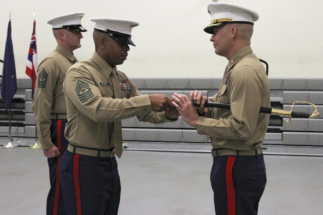Sgt. Maj. Spencer J. Beacham (center), the outgoing senior enlisted leader of Marine Corps Recruiting Station Orange County, returns the sword of office to Maj. James Dollard, his commanding officer, during a relief and appointment ceremony in Seal Beach, Caif., Jan. 15, 2016. During the ceremony, Beacham, from Dothan, Ala., was awarded a Meritorious Service Medal and relinquished duties to Sgt. Maj. Jason A. Politte.