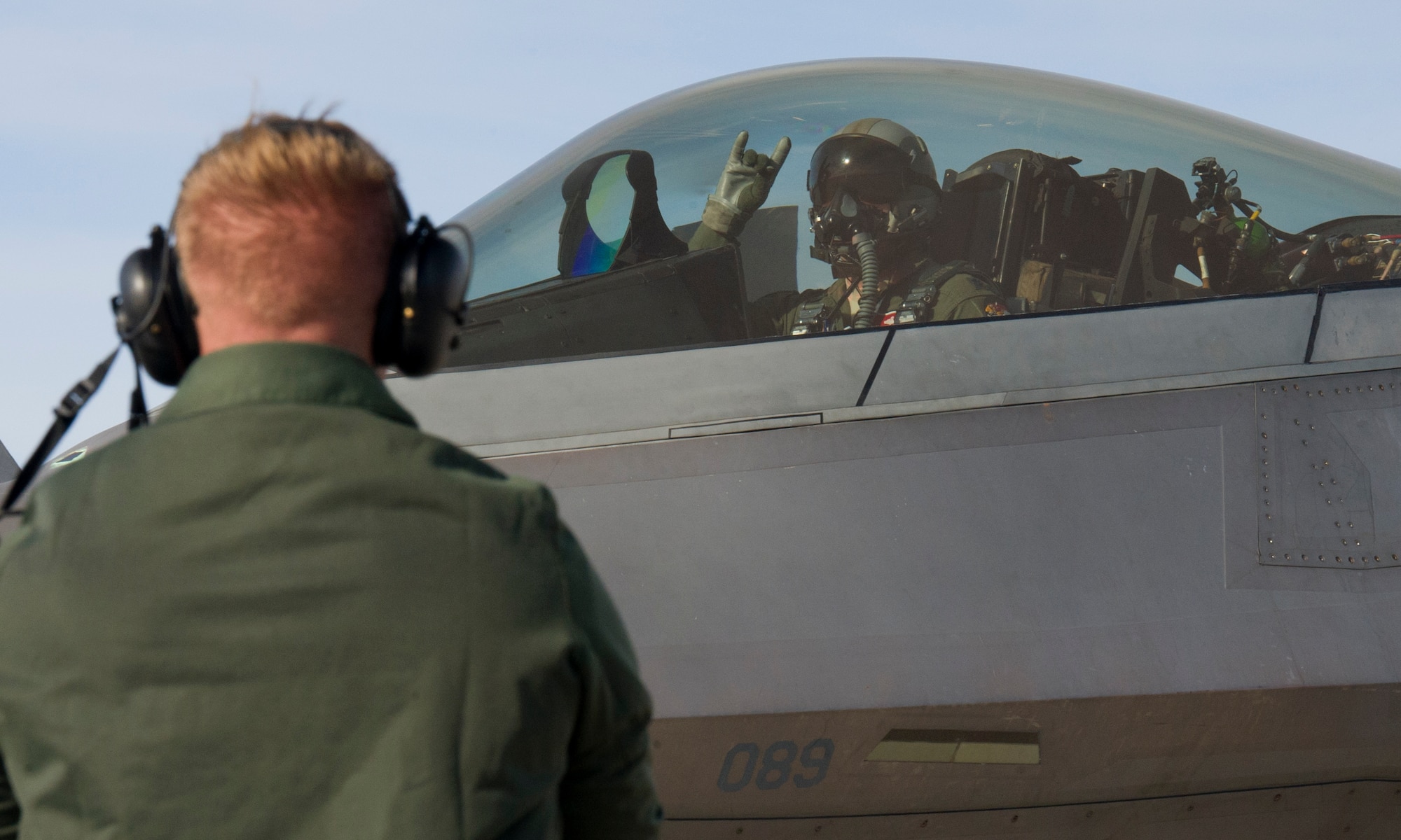 Lieutenant Colonel Matthew Fritz, 301st Fighter Squadron Director of Operations and F-22 Raptor pilot, and Airman 1st Class Nickalos Barnetine, 95th Aircraft Maintenance Unit crew chief, exchange gestures before takeoff, Jan. 25 on the Nellis AFB, Nev. flightline. More than 30 squadrons at Red Flag 16-1 will work together as they would in the field bringing them all together, possibly for the first time, before facing an actual threat. (U.S. Air Force photo by Senior Airman Alex Fox Echols III/Released)   