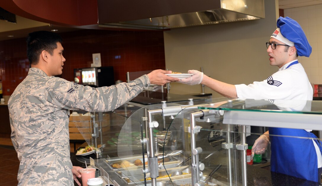 Airman 1st Class Joseph Manzanares, 28th Force Support Squadron, left, accepts his meal from Senior Airman Andrew Olvera, 28th FSS food services journeyman, in the Raider Café at Ellsworth Air Force Base, S.D., Jan. 26, 2016. The purpose of the Raider Café is to supply nutritious food for enlisted members living in the dorms, as well as those with base access who wish to use the facility. (U.S. Air Force photo by Airman Donald C. Knechtel/Released)