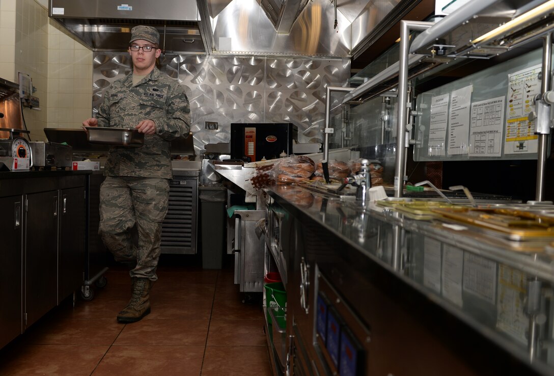 Senior Airman Luke Russell, 28th Force Support Squadron food services journeyman, prepares a meal line in the Raider Café at Ellsworth Air Force Base, S.D., Jan. 25, 2016. The café is composed of many stations including the deli, main entrees and u-food, which is a healthier option that provides customers with meals like bison and turkey burgers, and a smoothie and salad bar. (U.S. Air Force photo by Airman Donald C. Knechtel/Released)