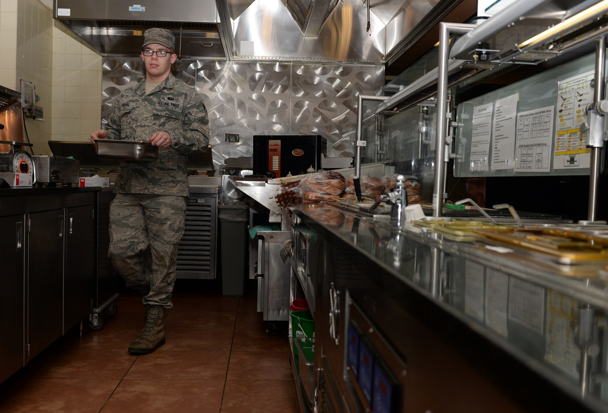 Senior Airman Luke Russell, 28th Force Support Squadron food services journeyman, prepares a meal line in the Raider Café at Ellsworth Air Force Base, S.D., Jan. 25, 2016. The café is composed of many stations including the deli, main entrees and u-food, which is a healthier option that provides customers with meals like bison and turkey burgers, and a smoothie and salad bar. (U.S. Air Force photo by Airman Donald C. Knechtel/Released)