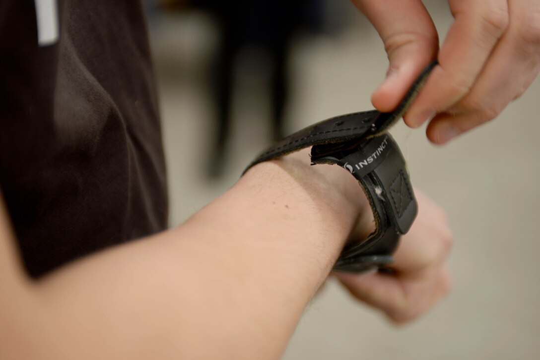 Airman 1st Class David Vogt, 28th Civil Engineer Squadron radio frequency transmission technician, straps a release to his wrist in the archery range at Ellsworth Air Force Base, S.D., Jan. 22, 2016. The release hooks onto a loop attached to a compound bow. Once the arrow is drawn back, a trigger is pressed to fire the arrow at a target. (U.S. Air Force photo by Airman Sadie Colbert/Released)