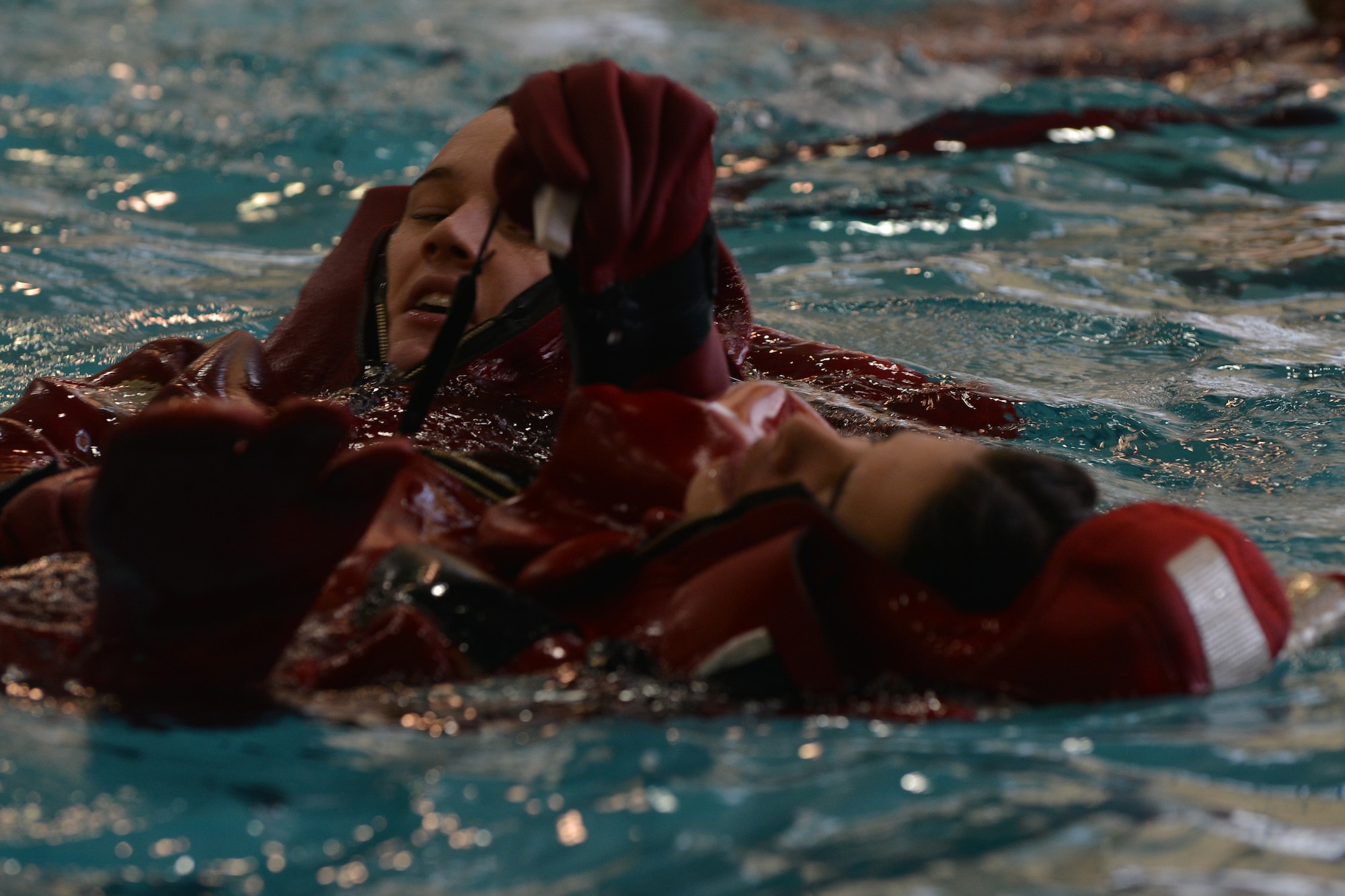 U.S. Army Soldiers help one another don survival suits in the water during survival swimming training at Fort Eustis, Va., Jan. 26, 2016. Maritime Intermodal Training Department students practiced to prepare for real-world emergencies.  (U.S. Air Force photo by Staff Sgt. Natasha Stannard)