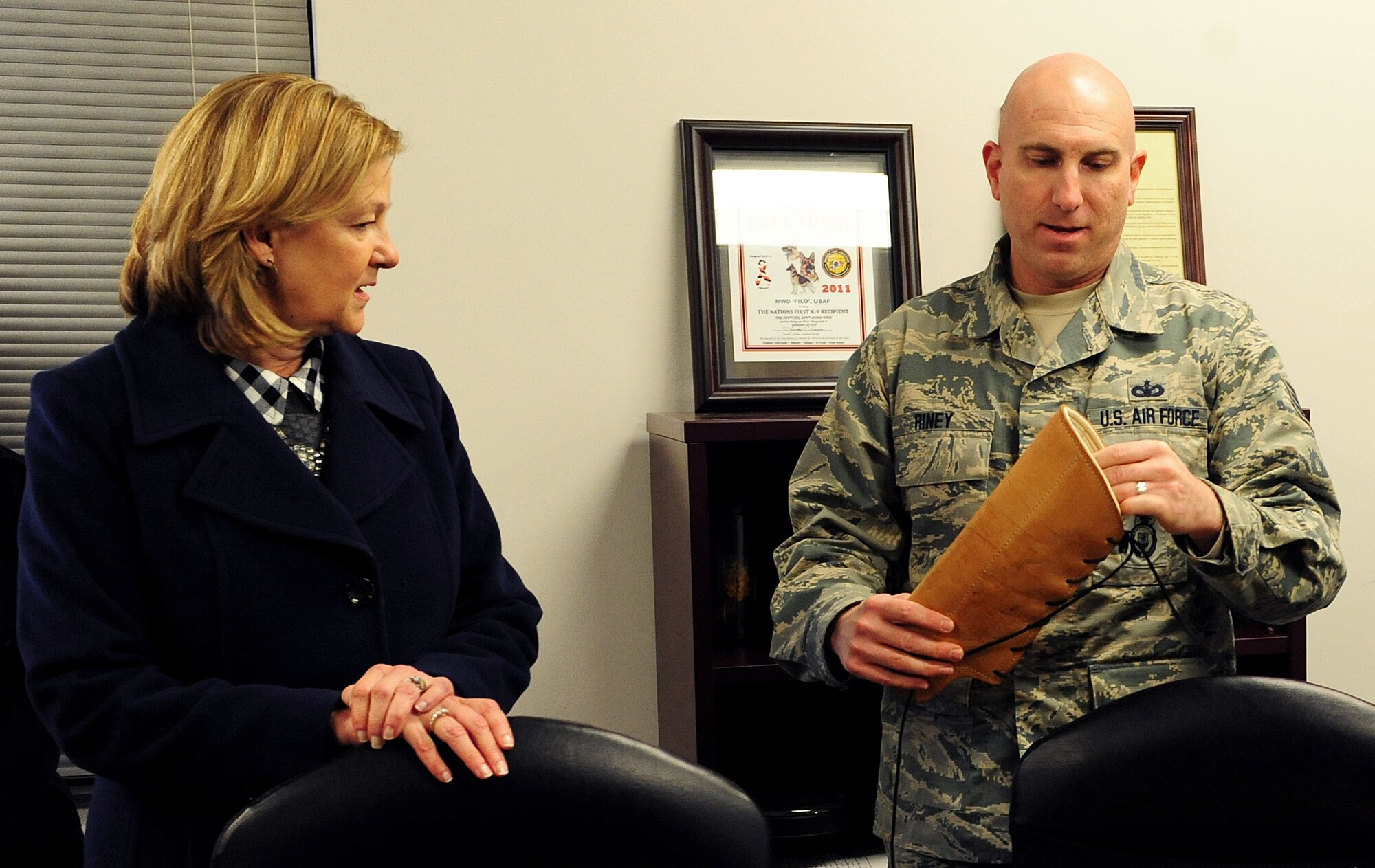 Tech. Sgt. William Riney, 509th Security Forces Squadron kennel master, shows Kim Rand, wife of AFGSC commander Gen. Robin Rand, different protection gear available to military working dog handlers for training during her visit to Whiteman Air Force Base, Mo., Jan. 20, 2016. After Rand’s tour of the kennels, the handlers performed a series of training exercises while explaining situations in which they would be used. (U.S. Air Force photo by Airman 1st Class Jazmin Smith)