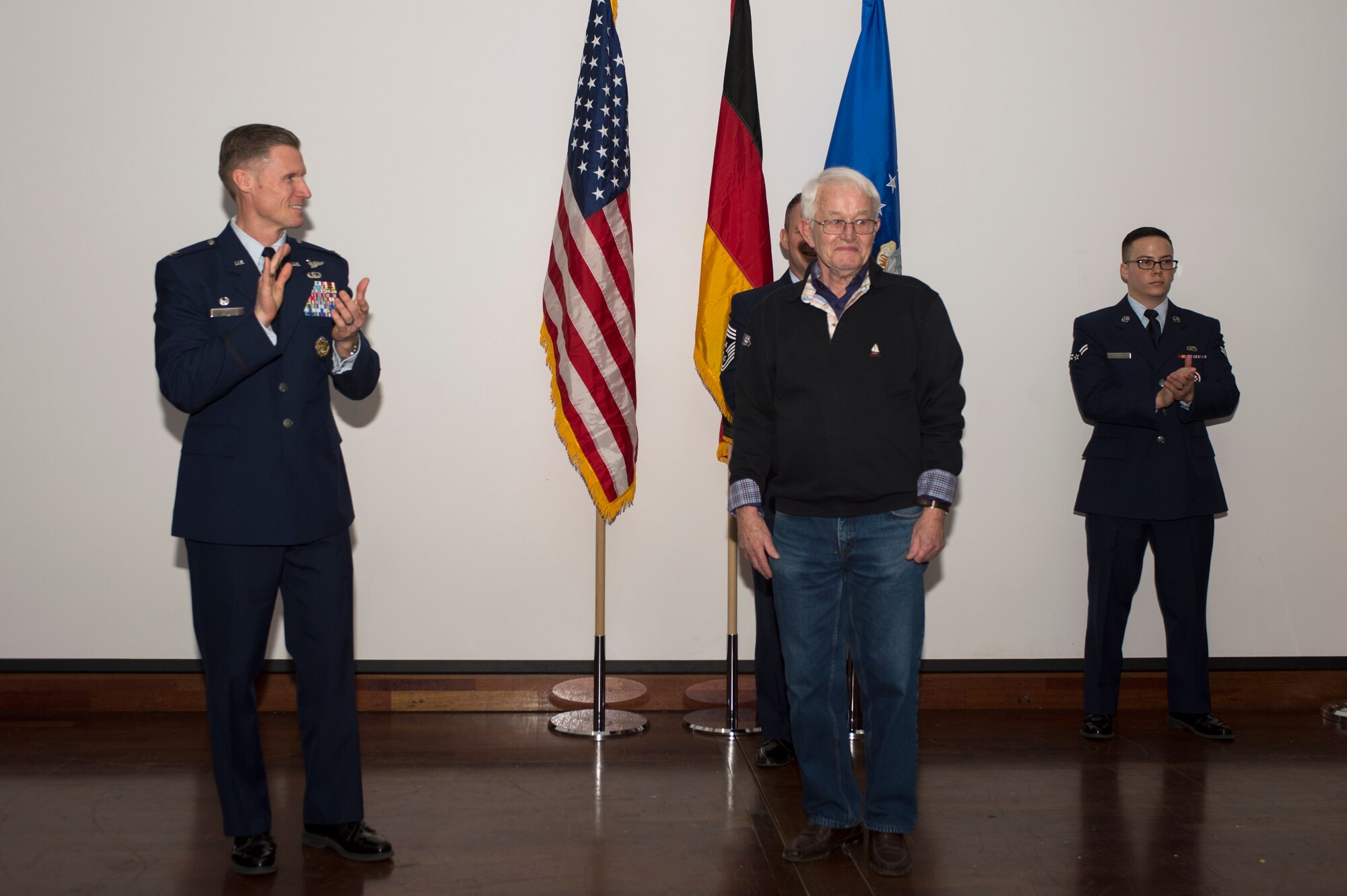 U.S. Air Force Col. Michael Thompson, left, leads an applause for Roger Feller, honorary 52nd OG commander, center during the Honorary Commander's Program graduation ceremony at Club Eifel on Spangdahlem Air Base, Germany, Jan. 22, 2016. Feller, who also owns and operates a World War II history museum in his city of Perle, Luxembourg, thanked the U.S. Air Force for the continuing partnership between the Airmen and the local communities. (U.S. Air Force photo by Staff Sgt. Joe W. McFadden/Released)
