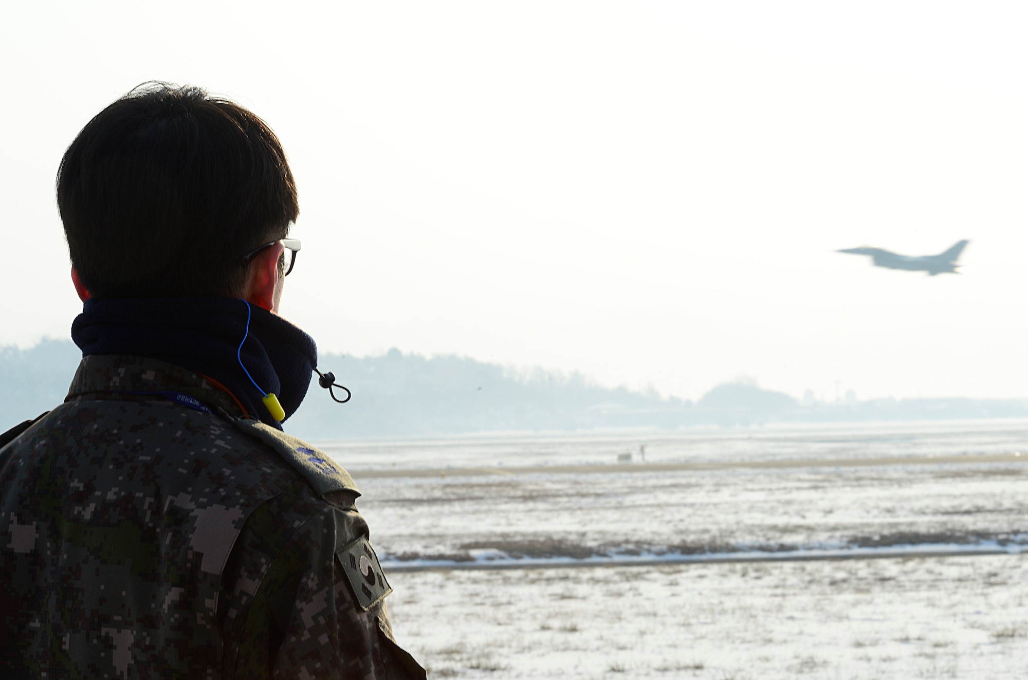 An airman from the Republic of Korea air force watches an F-16 Fighting Falcon from the 36th Fighter Squadron takeoff during Buddy Wing 16-1 at Seosan Air Base, ROK, Jan. 28, 2016. The Buddy Wing exercise is a combined fighter exchange program between the U.S. and ROKAF to promote solidarity and mutual understanding of all executed operations. (U.S. Air Force photo by Senior Airman Kristin High/Released)