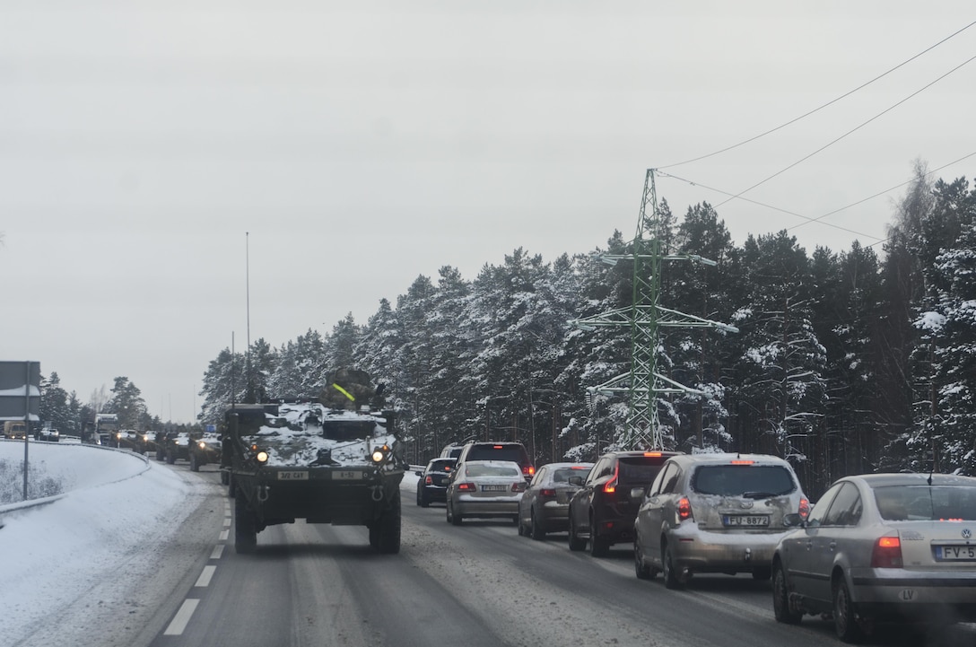Soldiers wave to passing vehicles as their convoy continues on its way to a Latvian army base in Adazi, Latvia, Jan. 14, 2016. Army photo by Staff Sgt. Steven Colvin